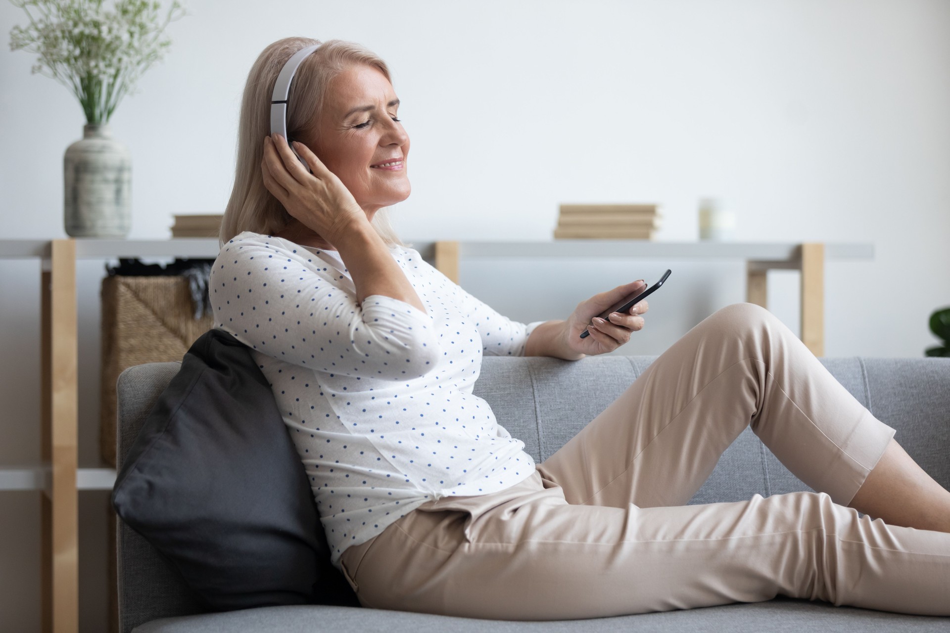 Calm woman wearing headphones listen mobile music at home
