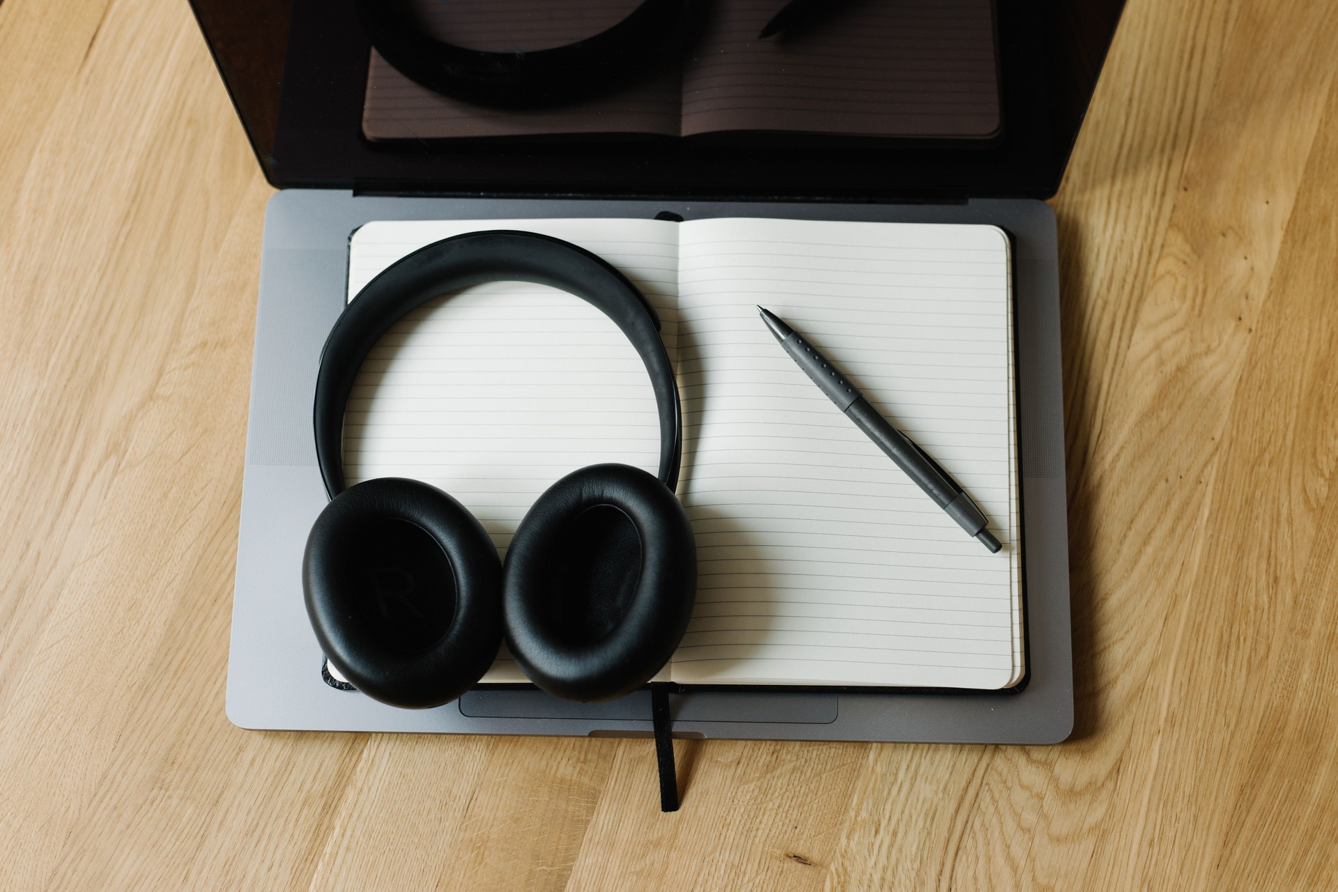 Earbuds with notebook and coffee near laptop